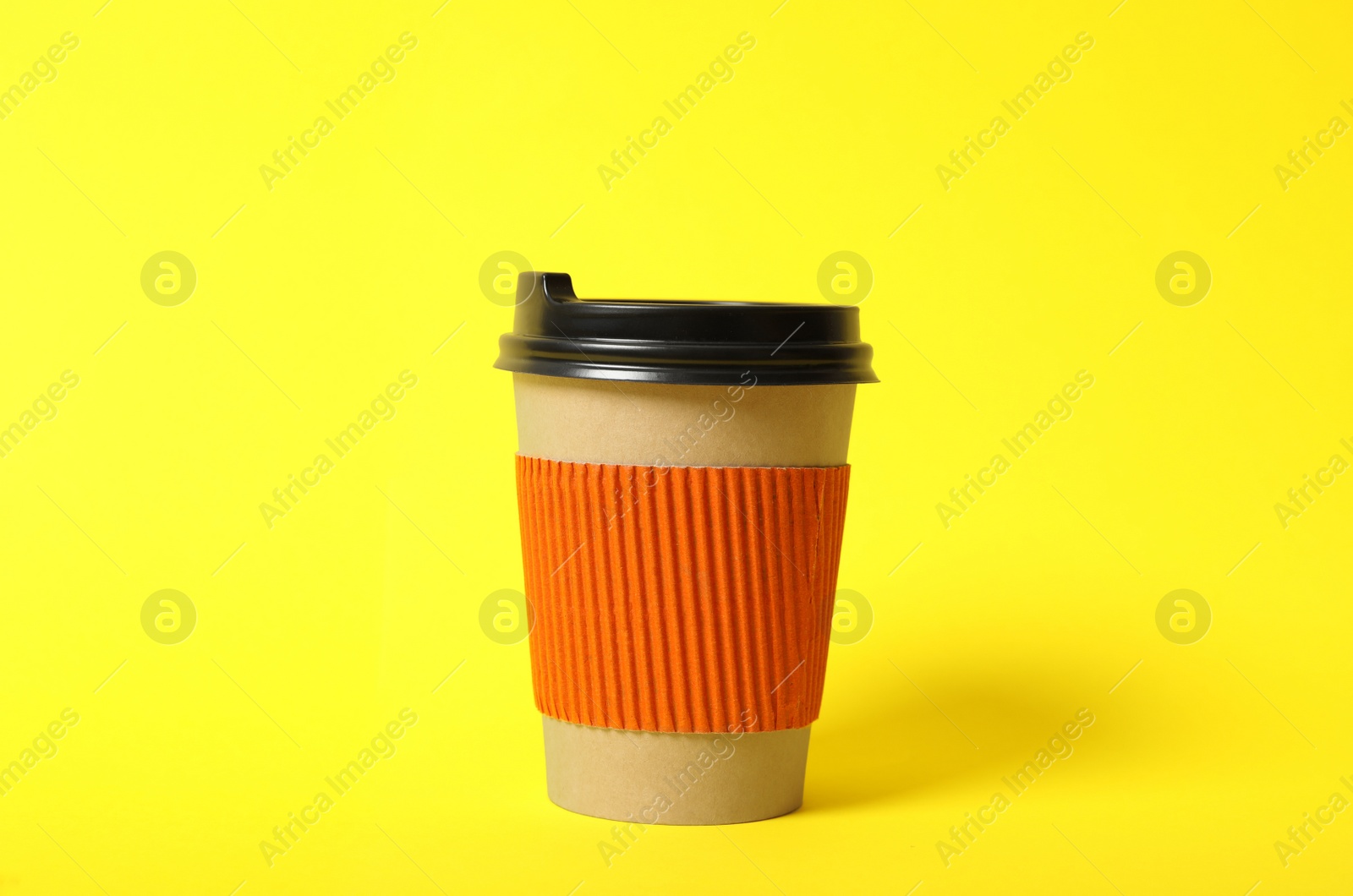 Photo of Takeaway paper coffee cup with cardboard sleeve on yellow background