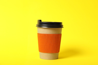 Takeaway paper coffee cup with cardboard sleeve on yellow background