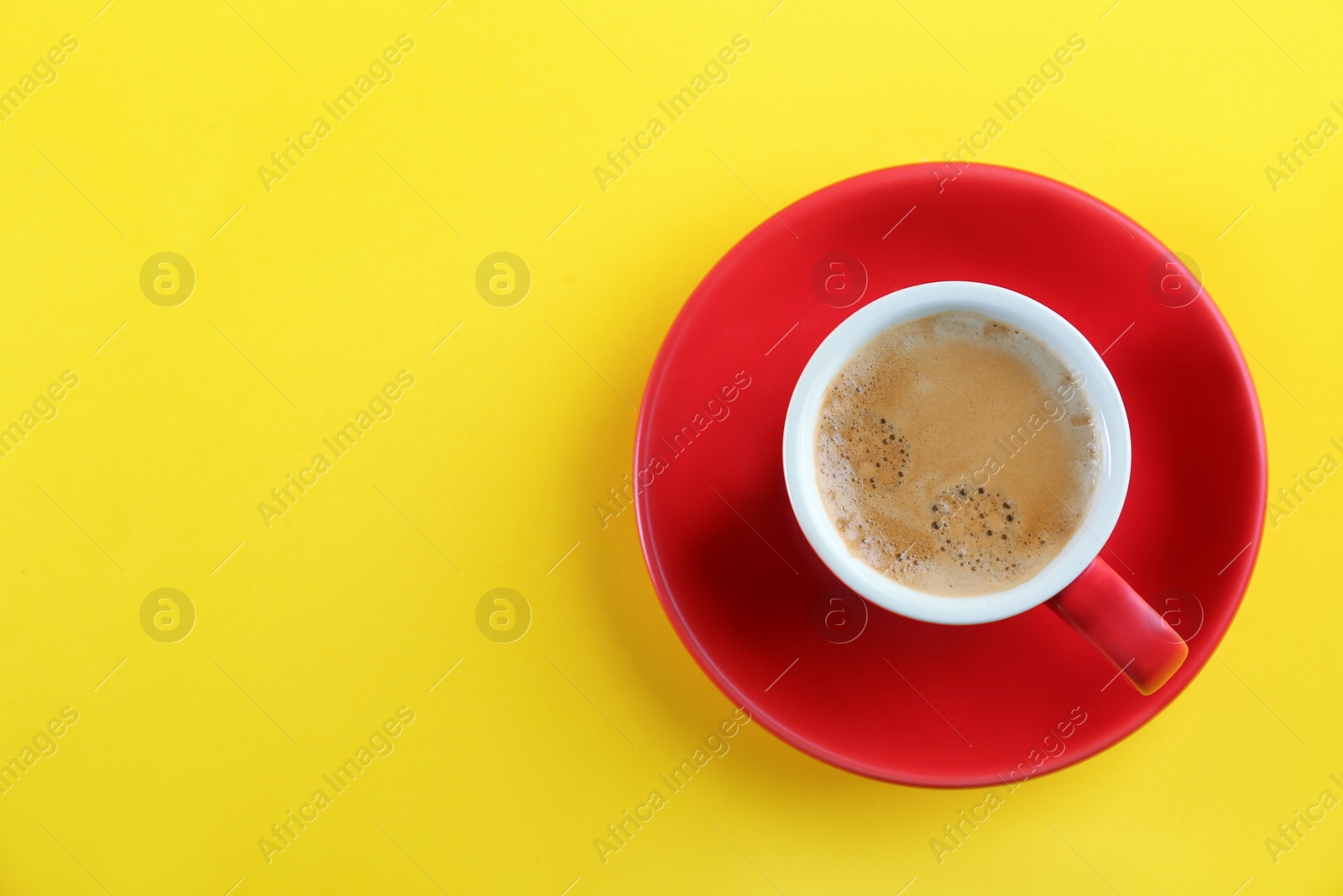 Photo of Cup of tasty coffee on yellow background, top view. Space for text