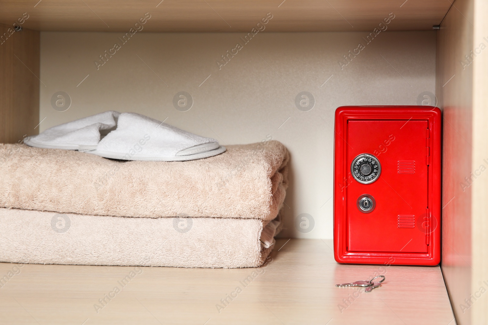 Photo of Red steel safe with mechanical combination lock on wooden shelf at hotel