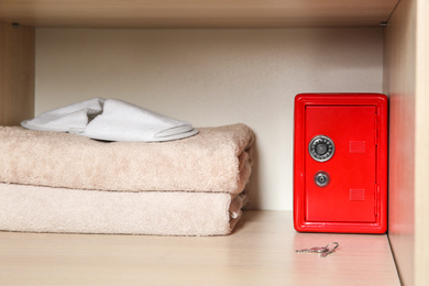 Photo of Red steel safe with mechanical combination lock on wooden shelf at hotel