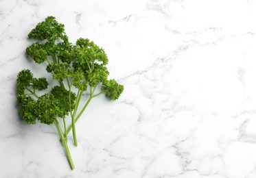 Fresh curly parsley on white marble table, flat lay. Space for text