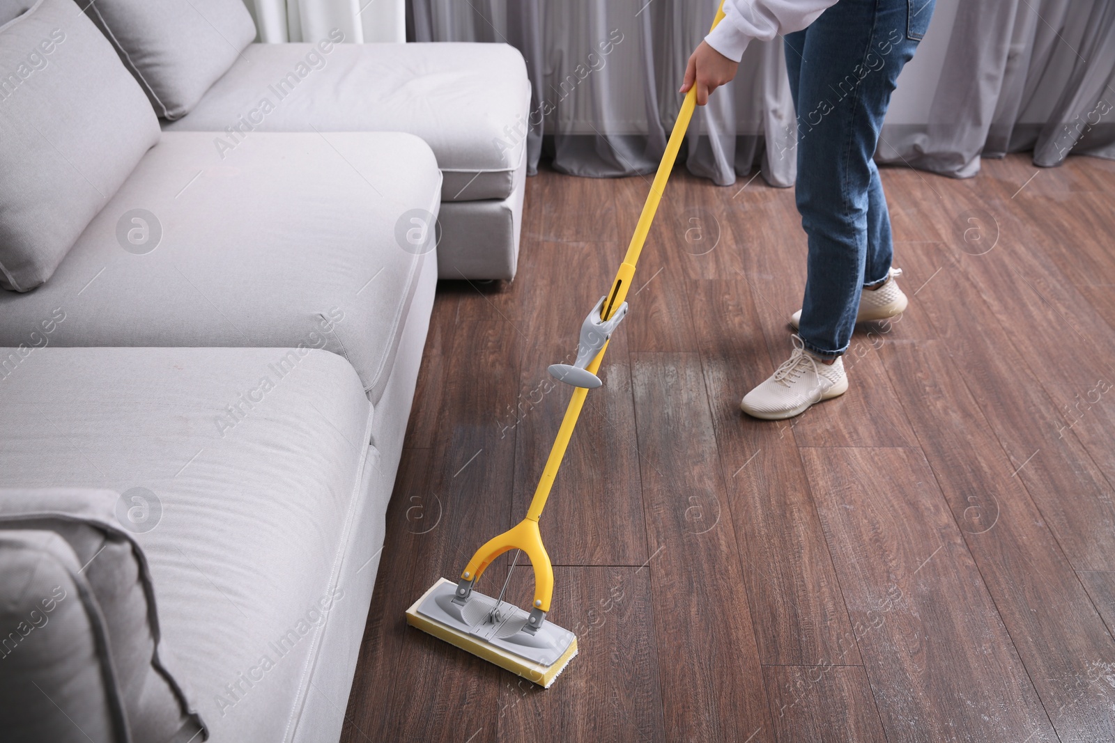 Photo of Woman cleaning parquet floor with mop indoors, closeup