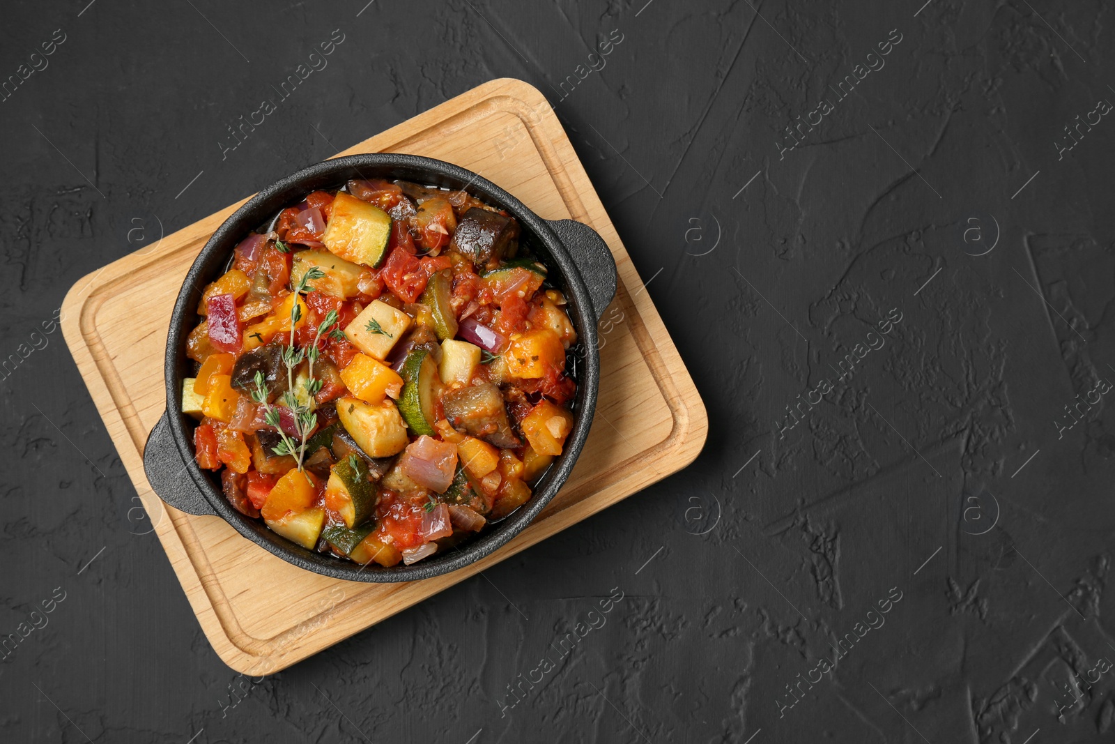 Photo of Dish with tasty ratatouille on black table, top view. Space for text