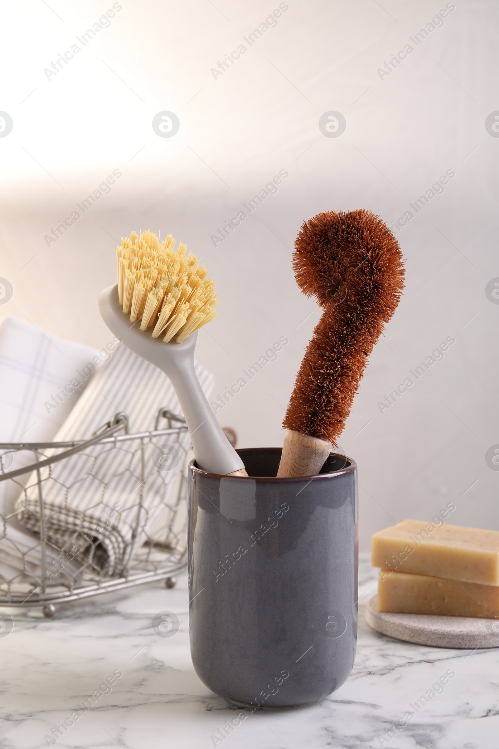 Photo of Brushes in holder and cleaning tools on white marble table