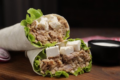 Photo of Delicious tortilla wraps with tuna on wooden board, closeup