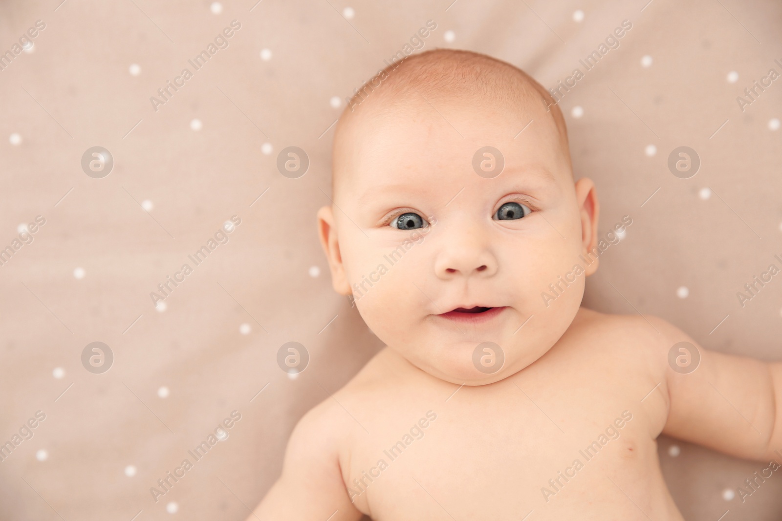 Photo of Adorable baby girl lying on bed, top view