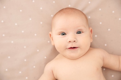 Adorable baby girl lying on bed, top view