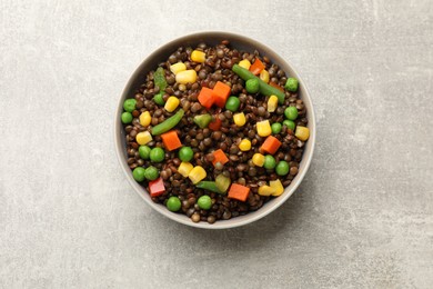 Photo of Delicious lentils with vegetables in bowl on light grey table, top view