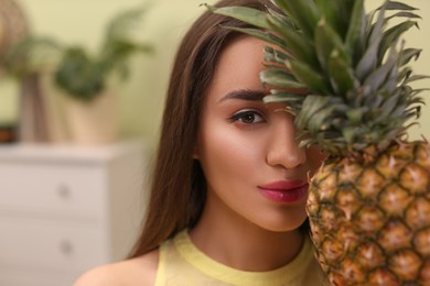 Young woman with fresh pineapple at home, space for text. Exotic fruit