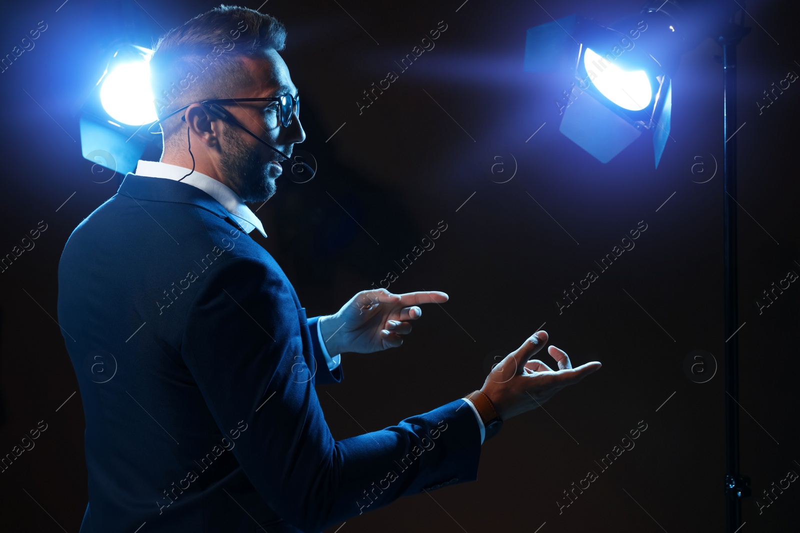 Photo of Motivational speaker with headset performing on stage. Space for text