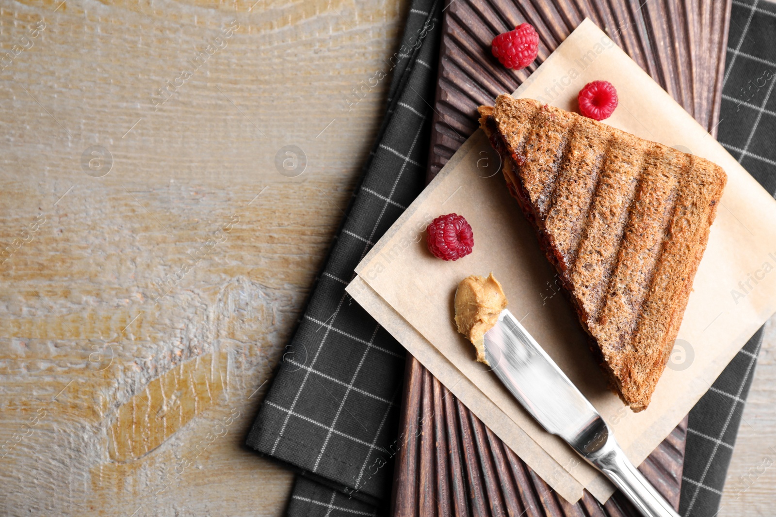 Image of Tasty sandwich with raspberry jam and peanut butter for breakfast on wooden table, flat lay