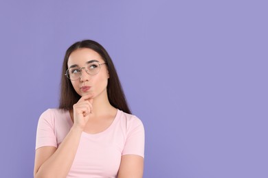 Photo of Curious woman wearing glasses on violet background, space for text