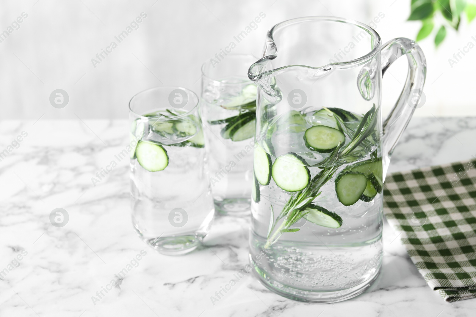 Photo of Refreshing cucumber water with rosemary in jug on white marble table, closeup