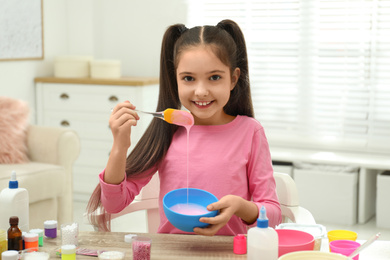 Cute little girl mixing ingredients with silicone spatula at table. DIY slime toy