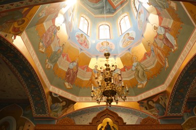 Beautiful church interior with chandelier and dome vault, low angle view