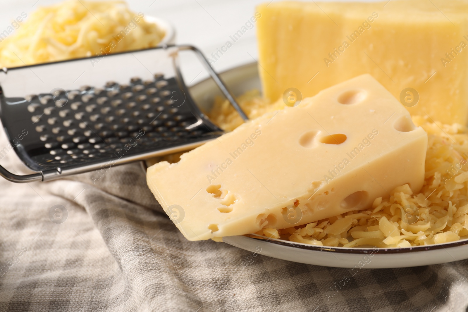 Photo of Grated and whole pieces of cheese on cloth, closeup