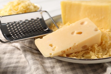 Photo of Grated and whole pieces of cheese on cloth, closeup