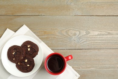 Photo of Tasty chocolate cookies and cup of coffee on wooden table, flat lay. Space for text