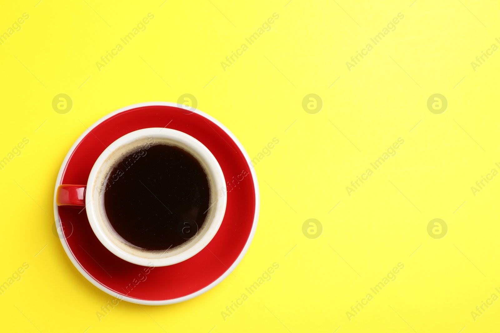 Photo of Aromatic coffee in cup on yellow background, top view. Space for text