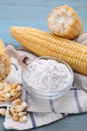 Bowl with corn starch, ripe cobs and kernels on light blue wooden table