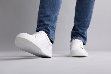 Photo of Man wearing stylish white sneakers on grey background, closeup