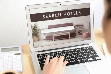 Woman searching hotel using laptop at table, closeup. Booking online service