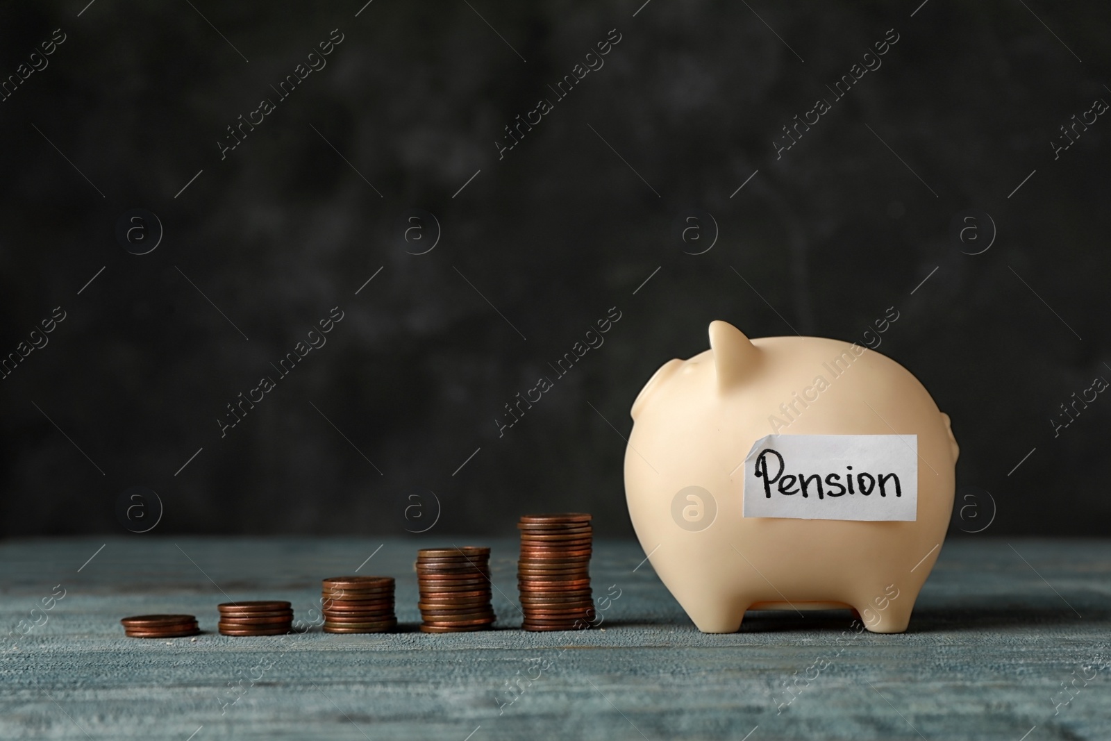 Photo of Piggy bank with word PENSION and coins on table. Space for text