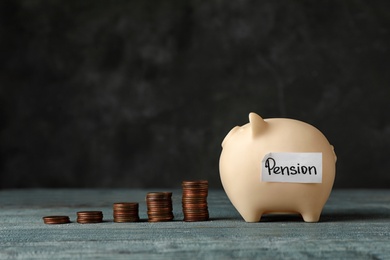 Piggy bank with word PENSION and coins on table. Space for text