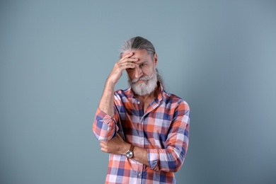 Photo of Handsome bearded mature man on color background