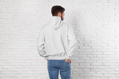 Photo of Young man in sweater at brick wall. Mock up for design