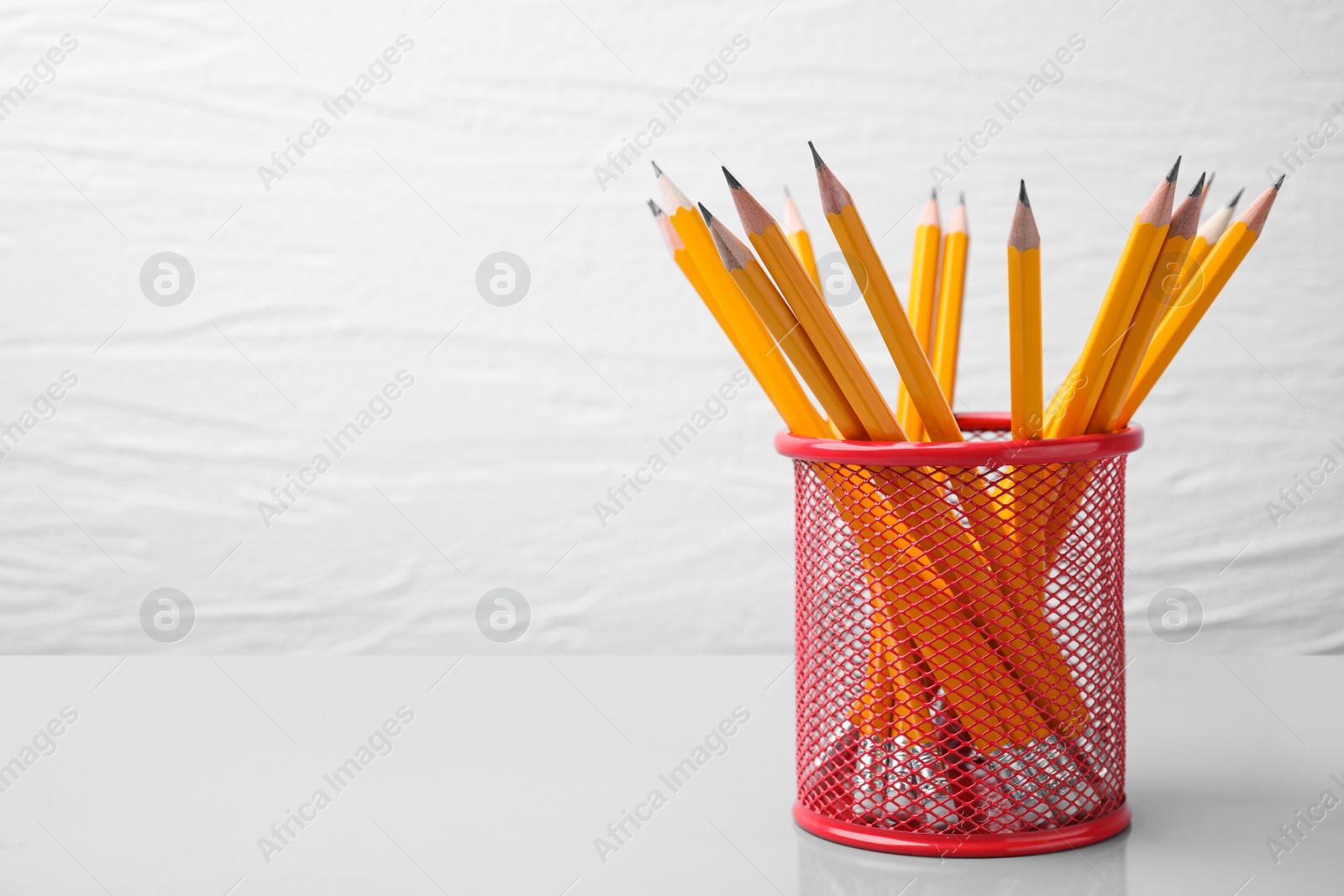 Photo of Many sharp pencils in holder on white background, space for text
