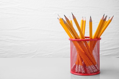 Photo of Many sharp pencils in holder on white background, space for text