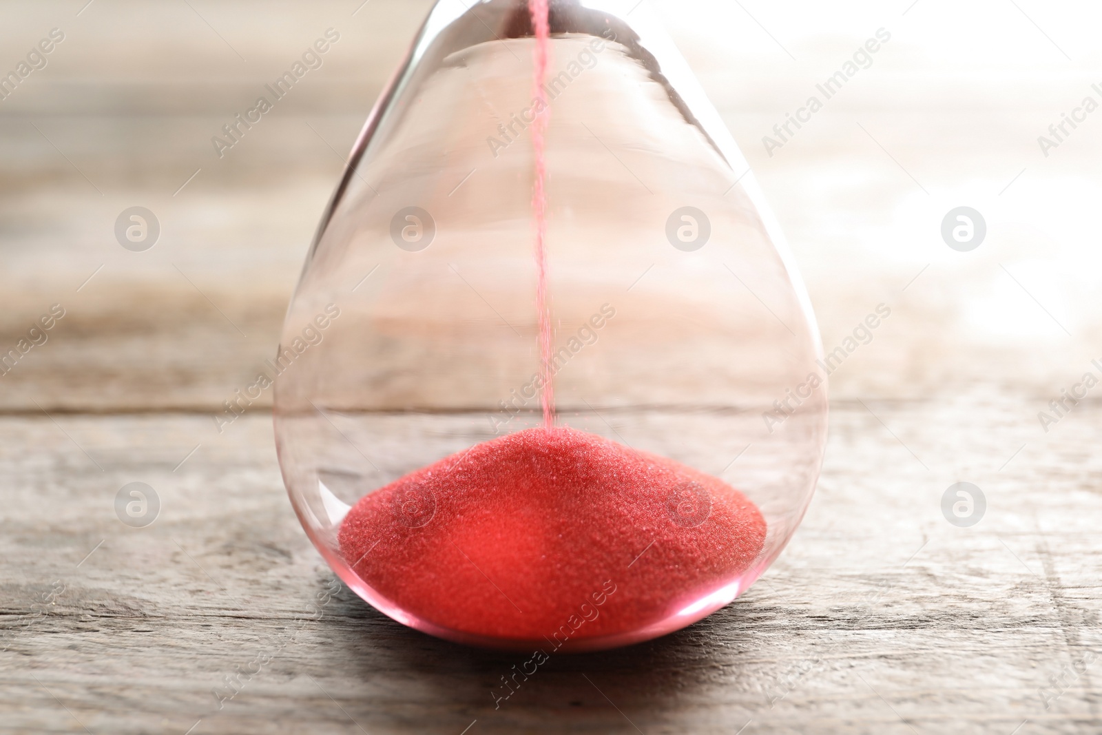 Photo of Hourglass with flowing sand on table, closeup. Time management