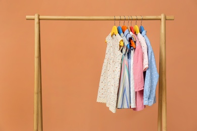 Rack with stylish children clothes on beige background