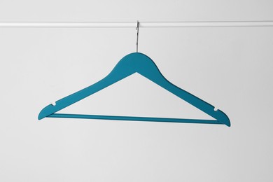 Blue clothes hanger on metal rail against light background