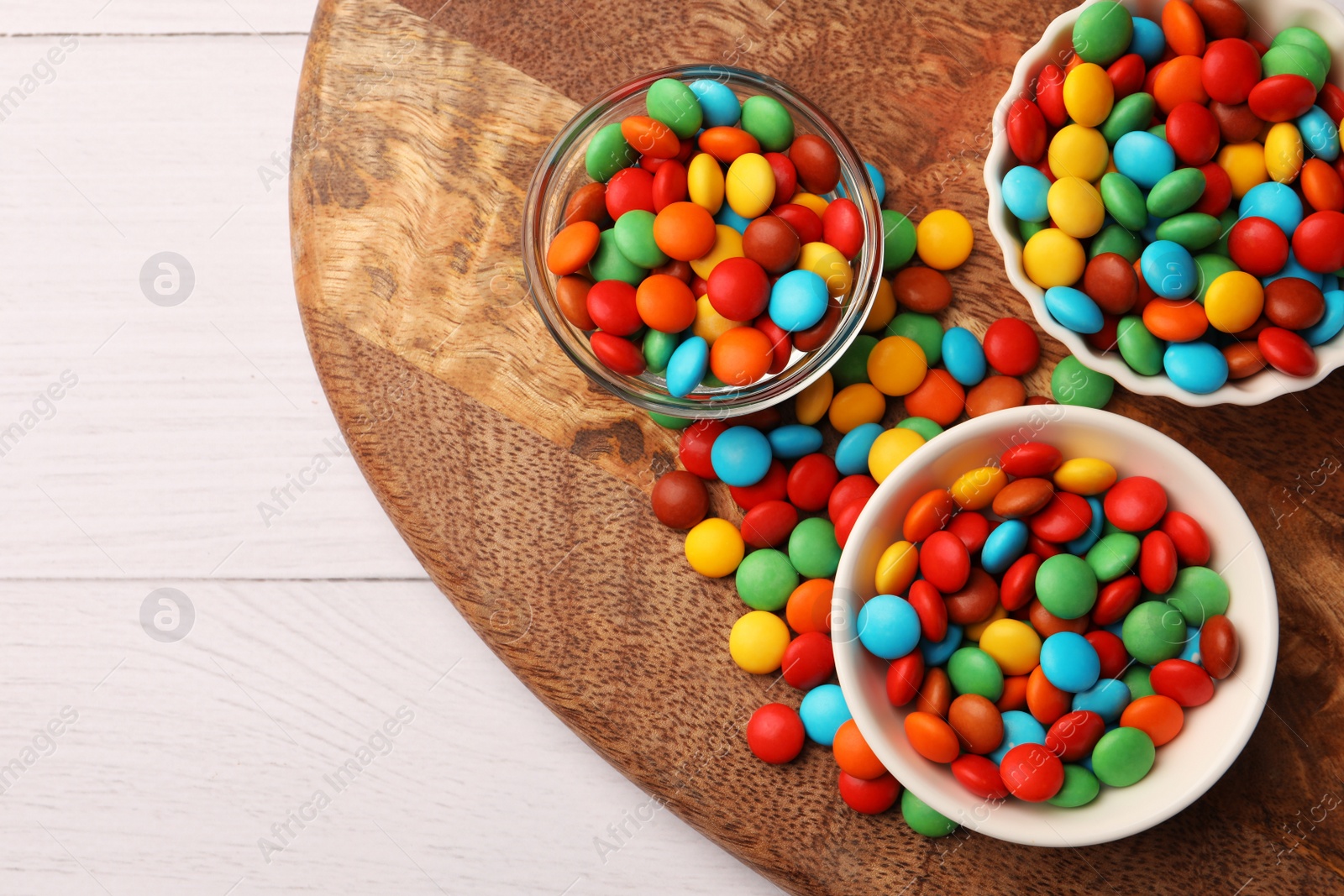 Photo of Tasty colorful candies on white wooden table, top view. Space for text