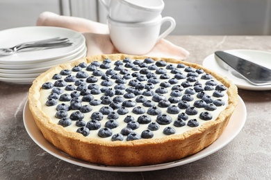 Photo of Plate with tasty blueberry cake on gray table