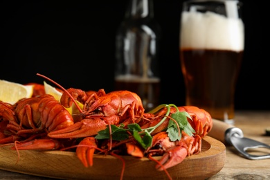 Delicious red boiled crayfishes and beer on wooden table, closeup