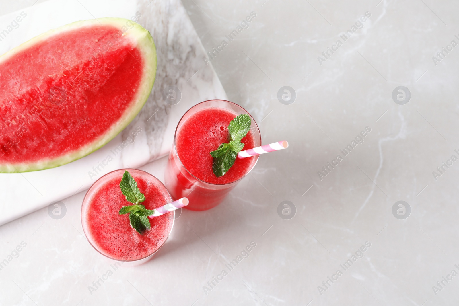 Photo of Tasty summer watermelon drink in glasses and fresh fruit on table. Space for text