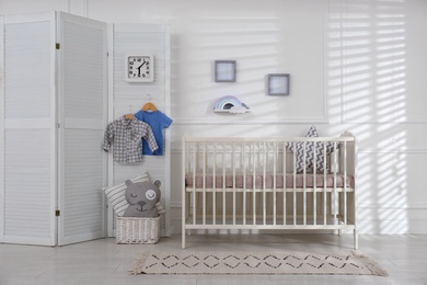 Cute baby room interior with comfortable crib and clock