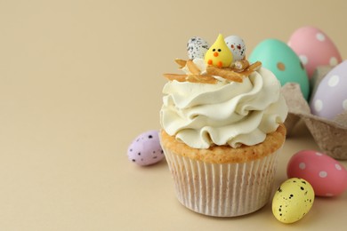 Photo of Tasty Easter cupcake with vanilla cream and candies on beige background, space for text