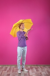 Man with yellow umbrella near color wall