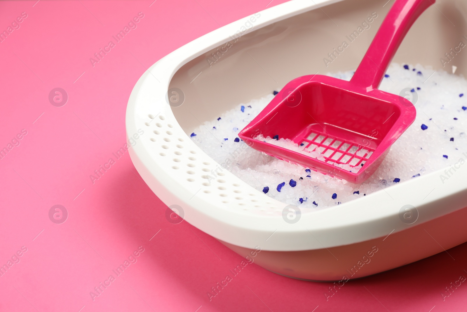 Photo of Cat litter tray with filler and scoop on pink background, closeup