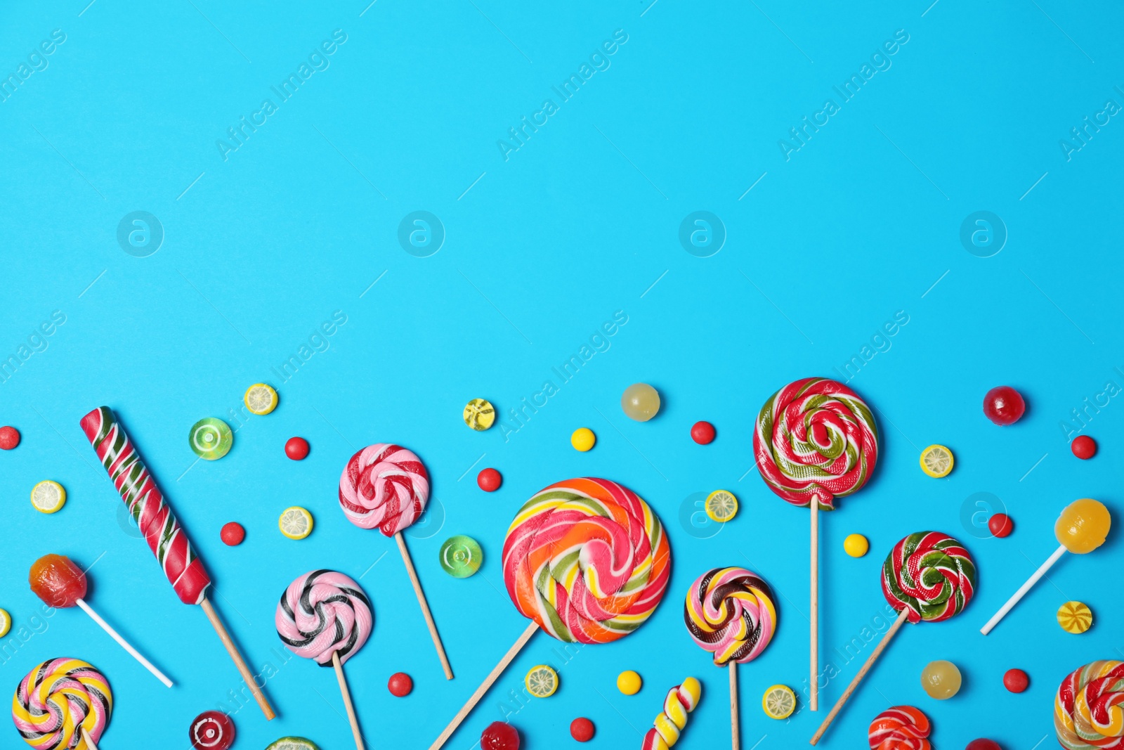 Photo of Bright yummy candies and space for text on color background, flat lay