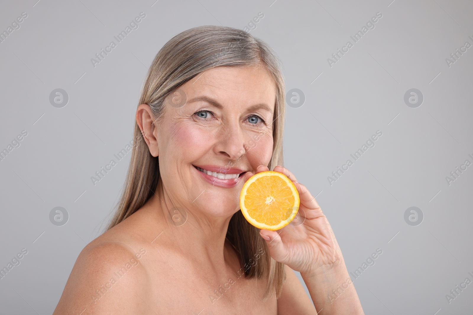 Photo of Beautiful woman with half of orange rich in vitamin C on grey background