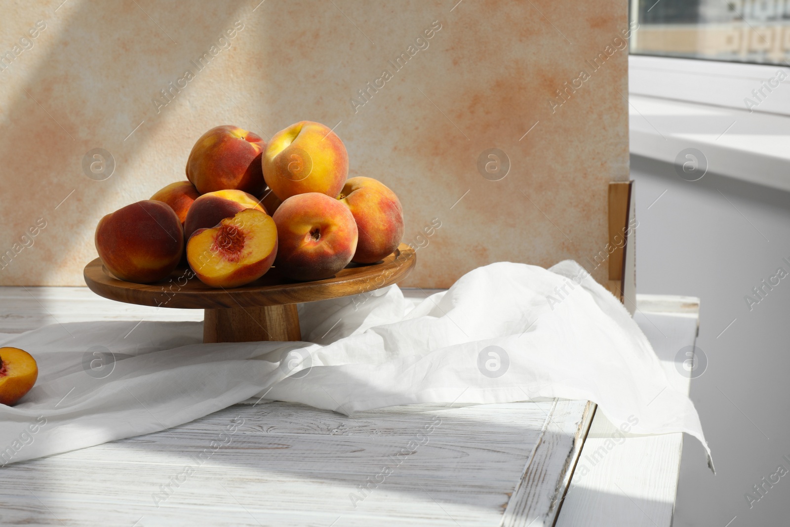 Photo of Stand with juicy peaches and double-sided backdrop in photo studio