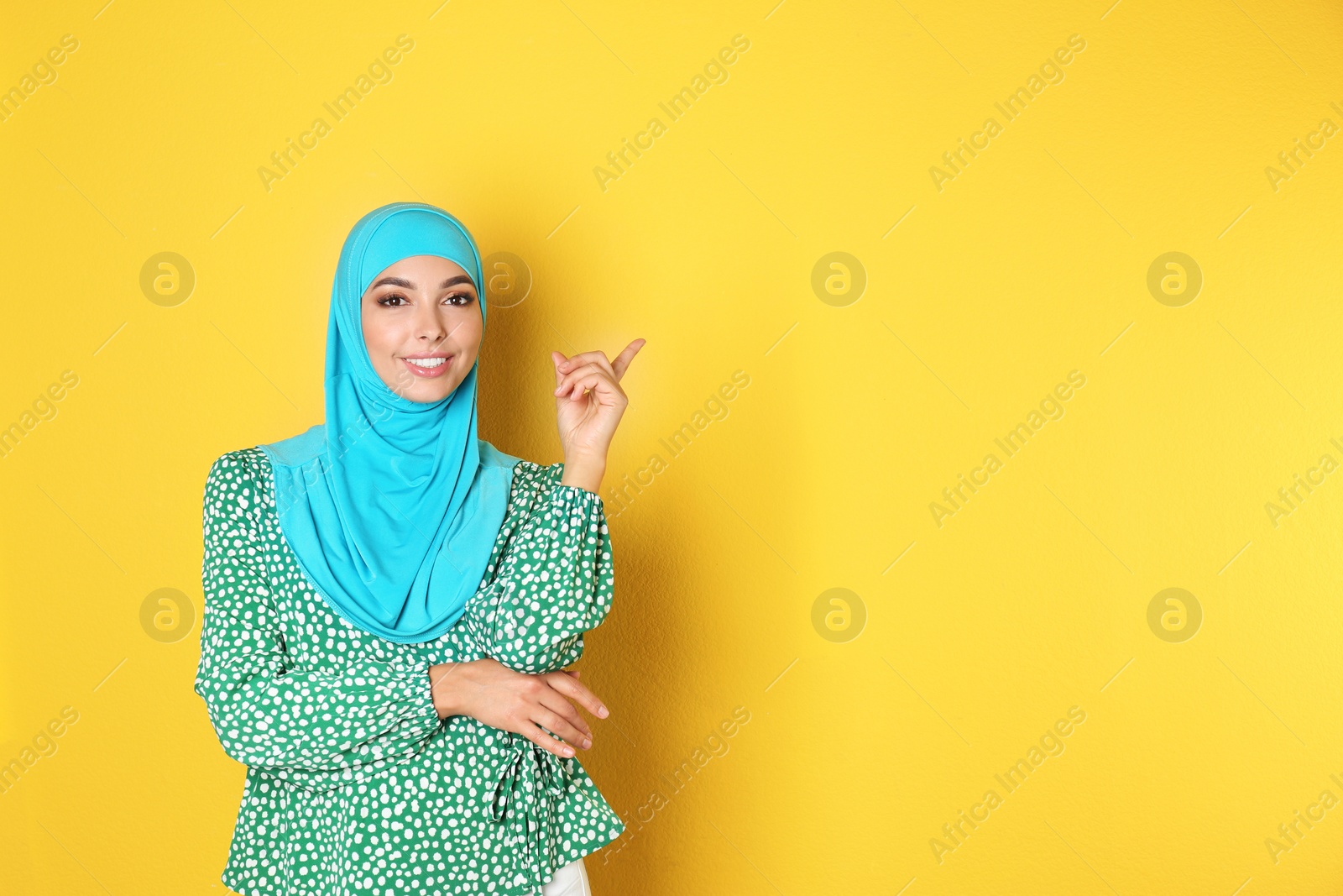 Photo of Portrait of young Muslim woman in hijab against color background. Space for text