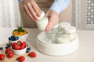 Photo of Woman making tasty yogurt at white wooden table in kitchen, closeup