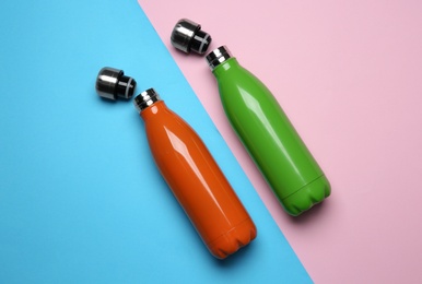 Photo of Modern thermo bottles on color background, flat lay